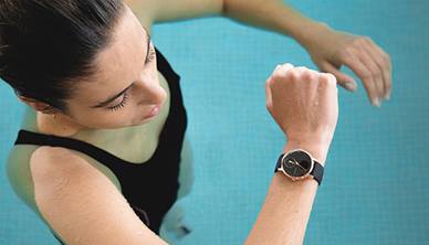 Woman swimming and looking at fitness tracker in swimming pool