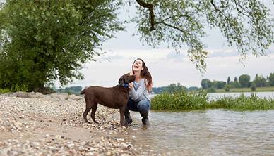 Women hugging dog by a river