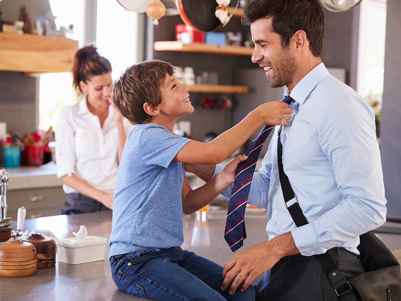 Boy tugging at man's tie in family house