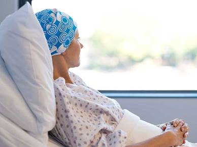 A cancer patient in a hospital bed looking out of the  window