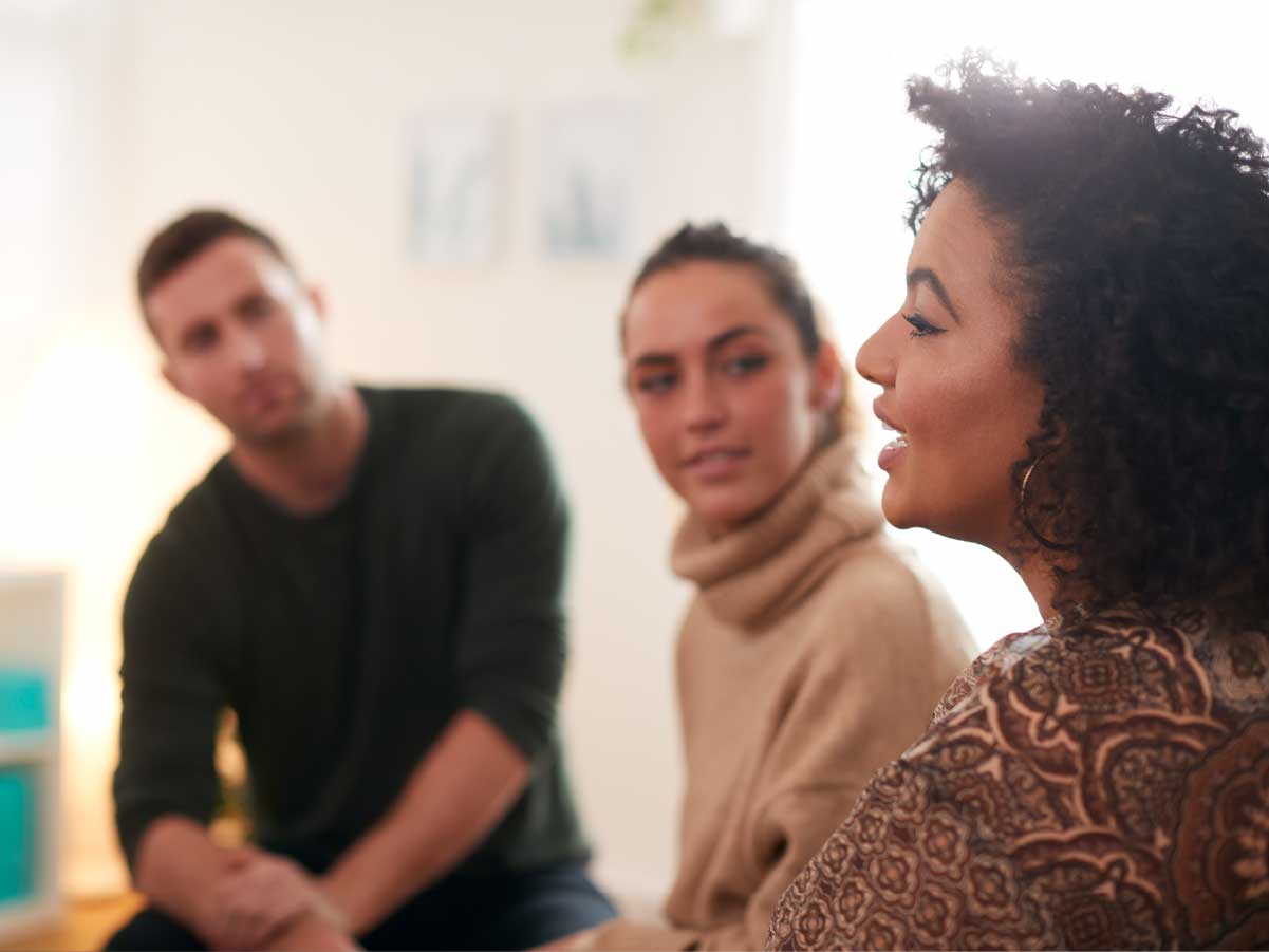 A woman talking infront of a man and woman