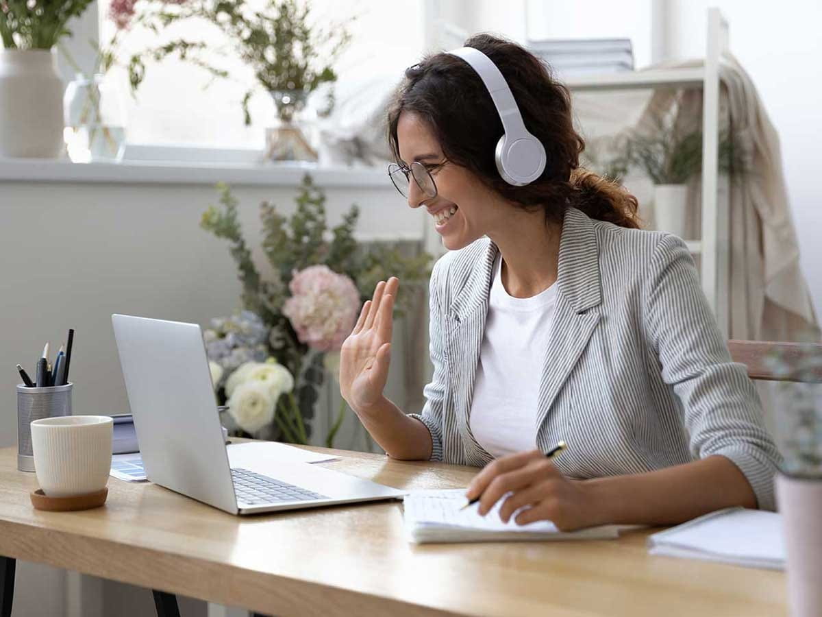 Woman waving to the person she is talking to online