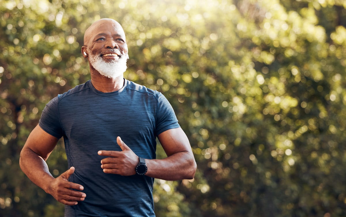 Happy black man running in park with music