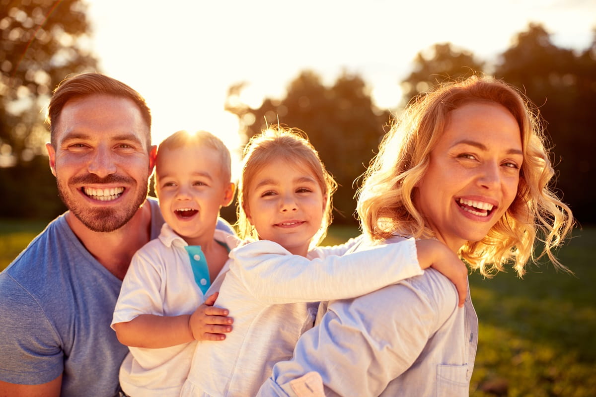 Happy young family with two kids enjoying in nature smiling 1200