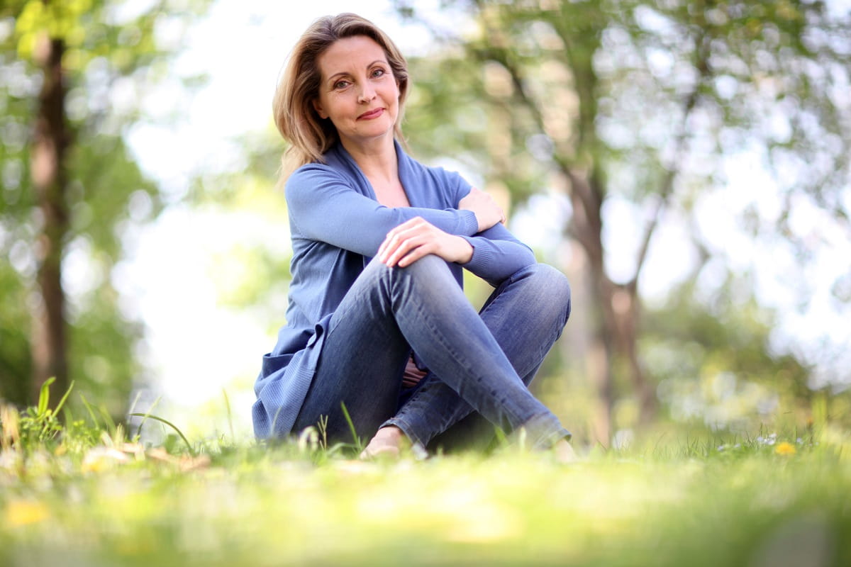 woman sitting in the park smiling menopause health mental health