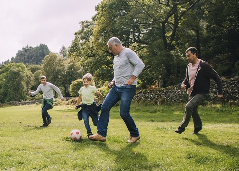 father playing football with family