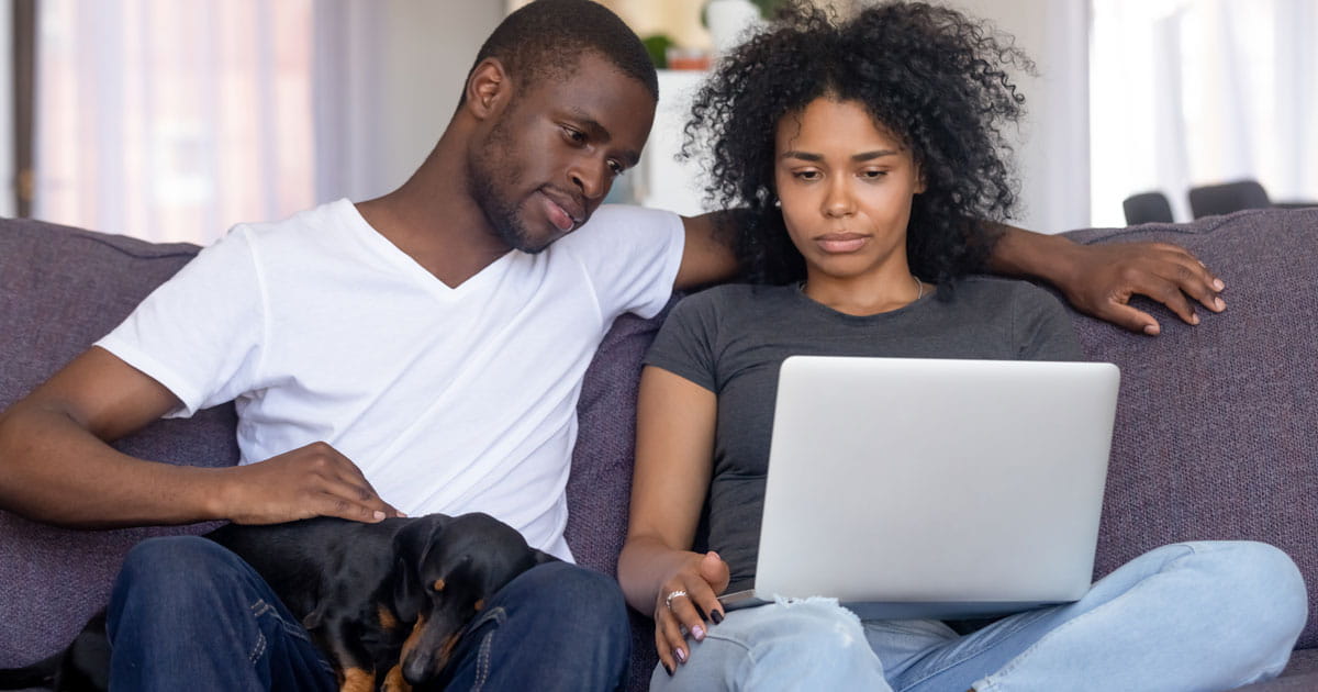 Couple and dog on couch with laptop