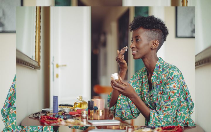 Black woman applying cream to her face at home