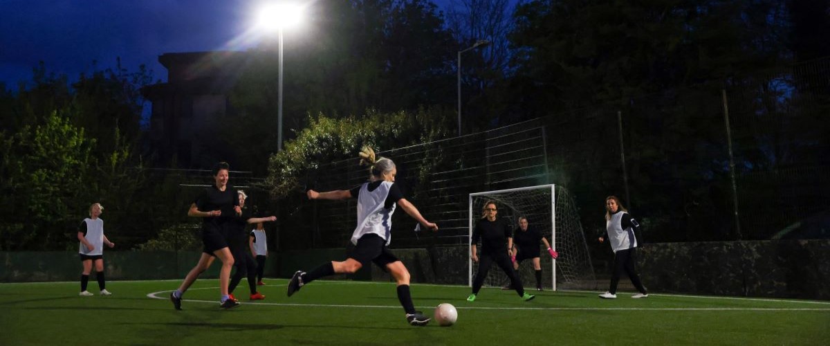 Female footballers play against on another at night