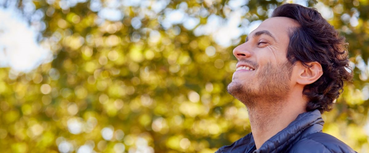 man taking a breath on fresh air smiling outside