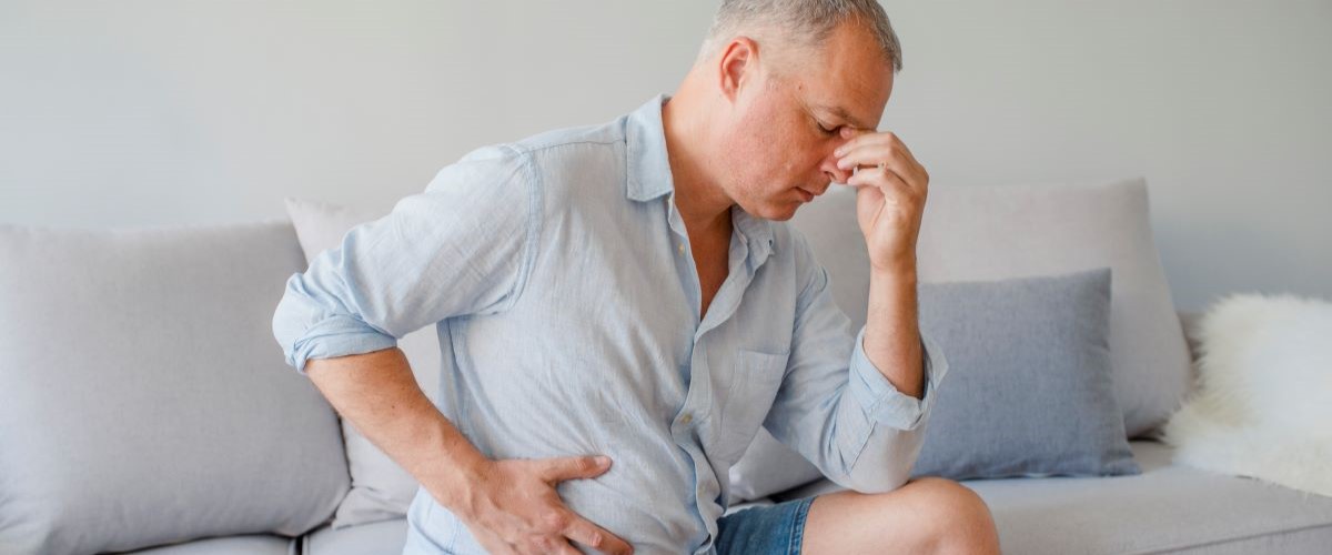 man sat on sofa with bowel touching stomach