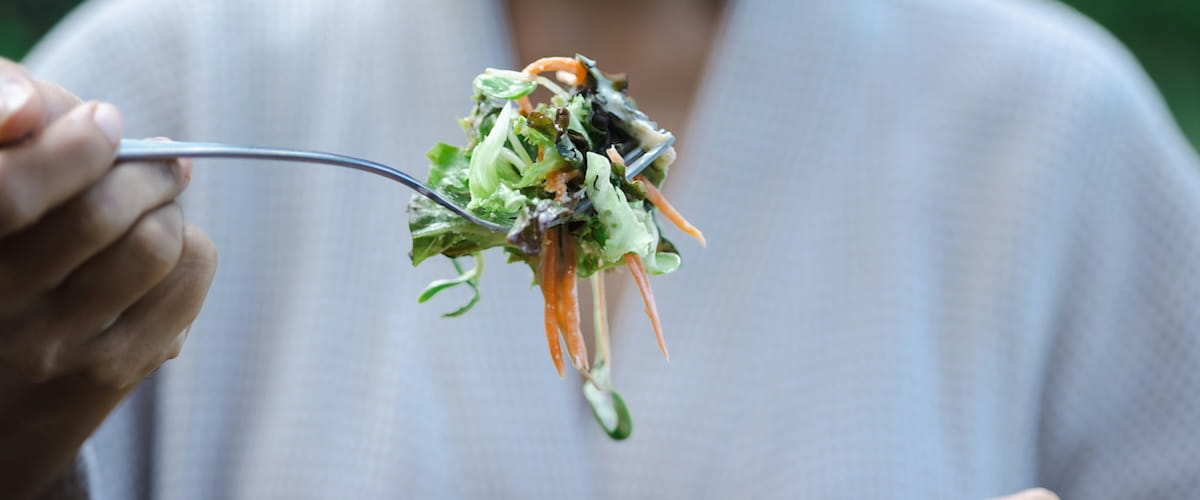 Shot of a woman preparing and eating fruit before making a smoothie