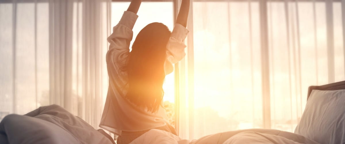 women-stretching-in-bed-with-morning-sun