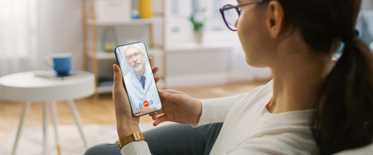 Woman looking at a phone on a virtual GP appointment